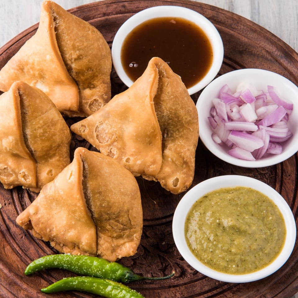 Clayoven Indian Cuisine samosas with green chutney, tamarind chutney, and diced red onions.